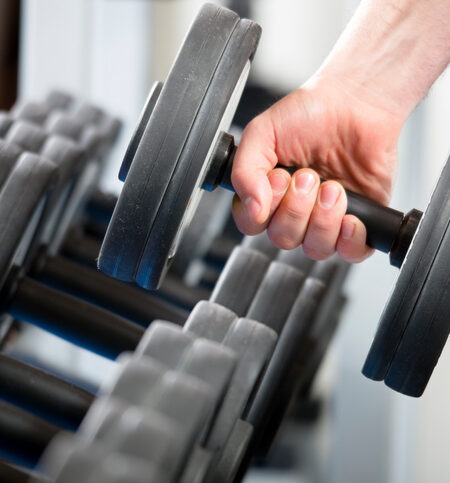 close up of man holding weight in gym
